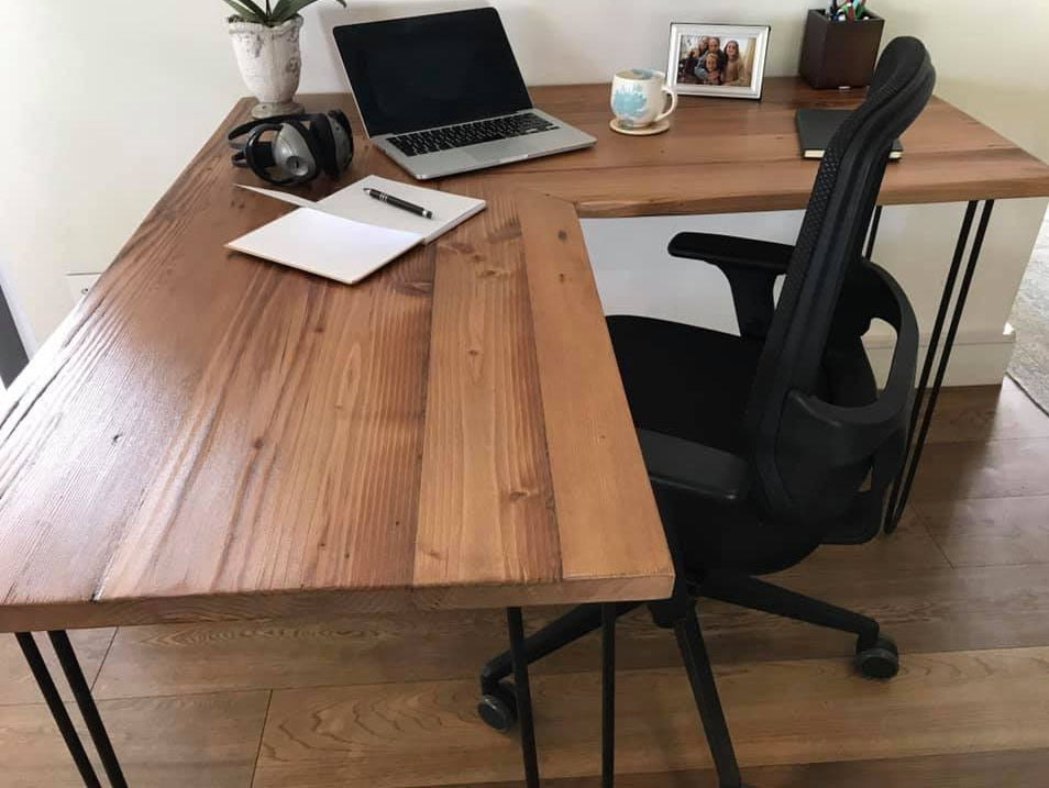 Custom made wooden L-shaped desk with black tubular metal legs.