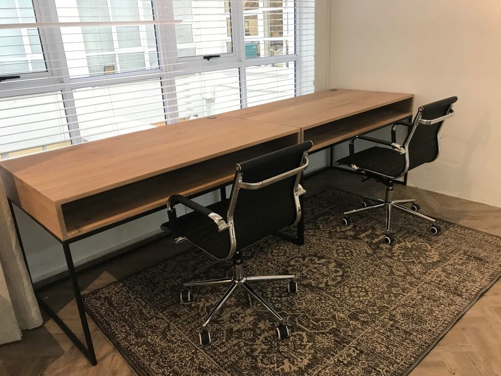 Long wooden custom made desks with central storage space and sturdy black metal legs.