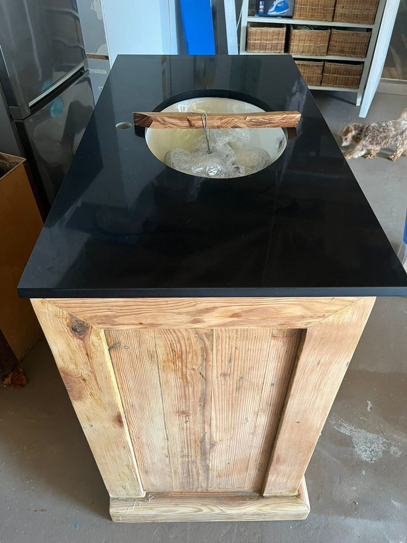 Custom made wooden bathroom cabinet with a black countertop.