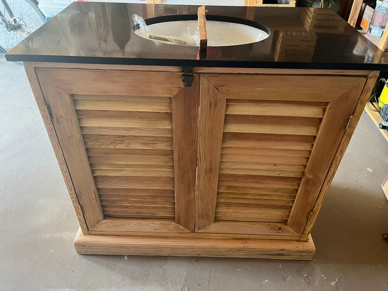 Wooden bathroom vanity with black countertop and sink