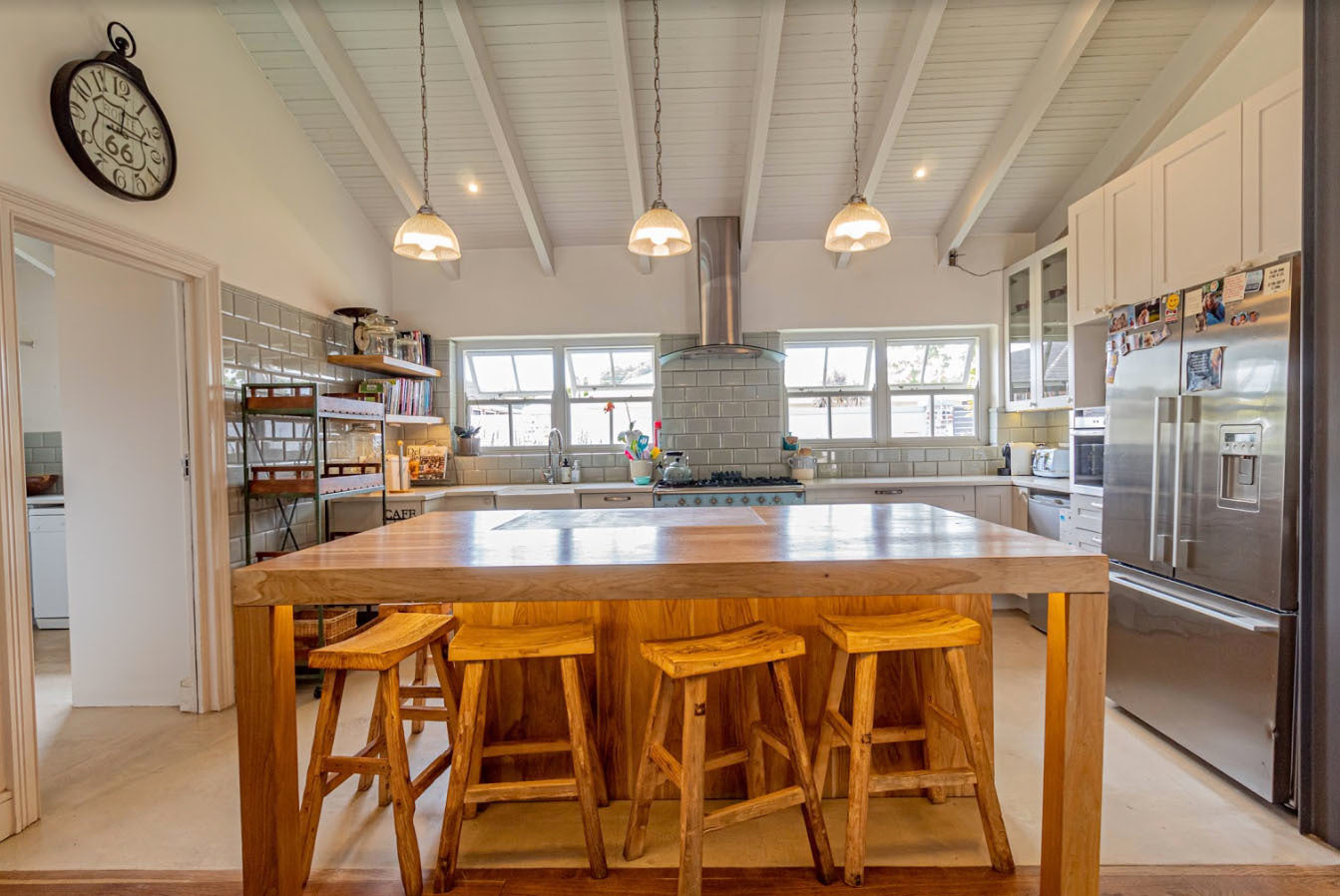 Modern kitchen with wooden island and stools. 