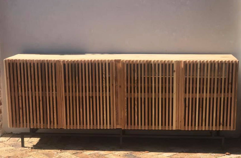Custom made wooden tv unit on black metal leg with slatted doors. 