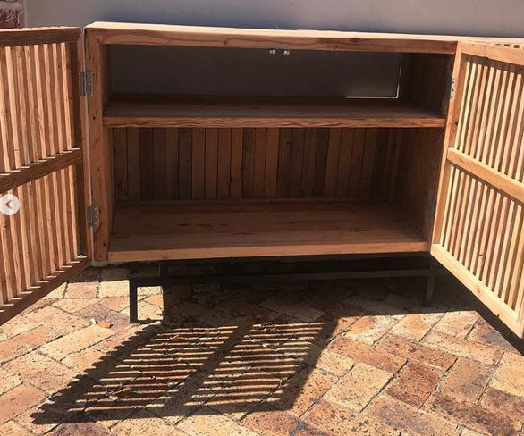 Custom made wooden tv unit with slatted doors and black metal legs.