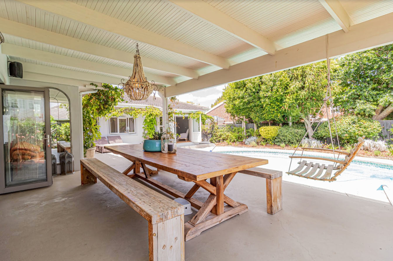 Custom made outdoor wooden table with cross leg design and wooden benches.