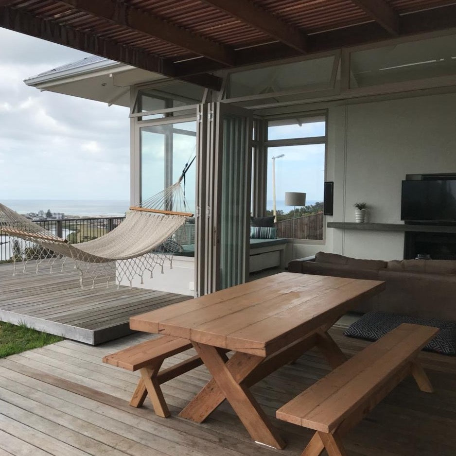 The Frank Cross Leg Table features a solid timber top and a classic cross-leg base. Optional matching benches available. Custom made to order in SA.