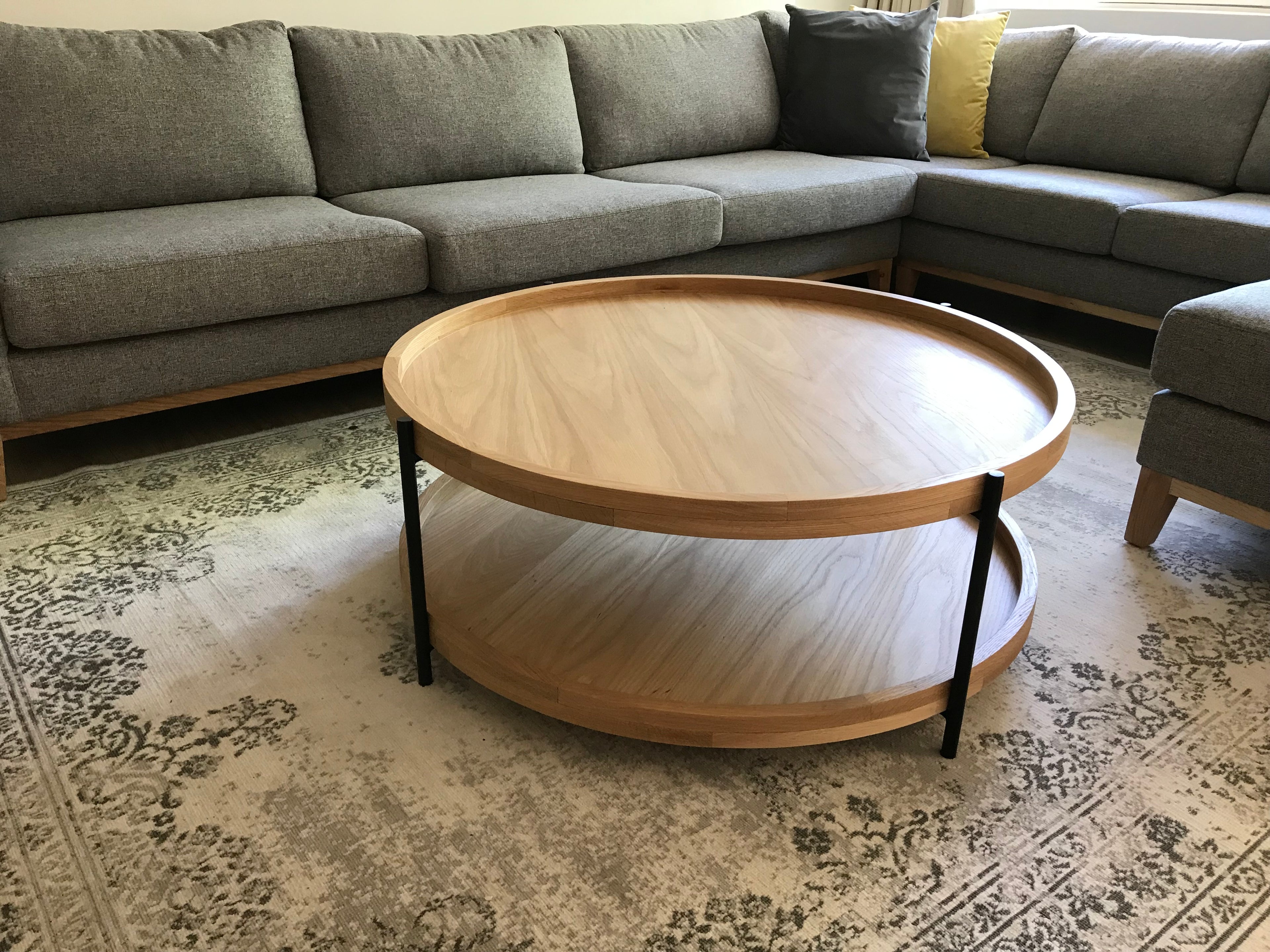Double tiered round oak coffee table with black tubular frame and legs in living room.