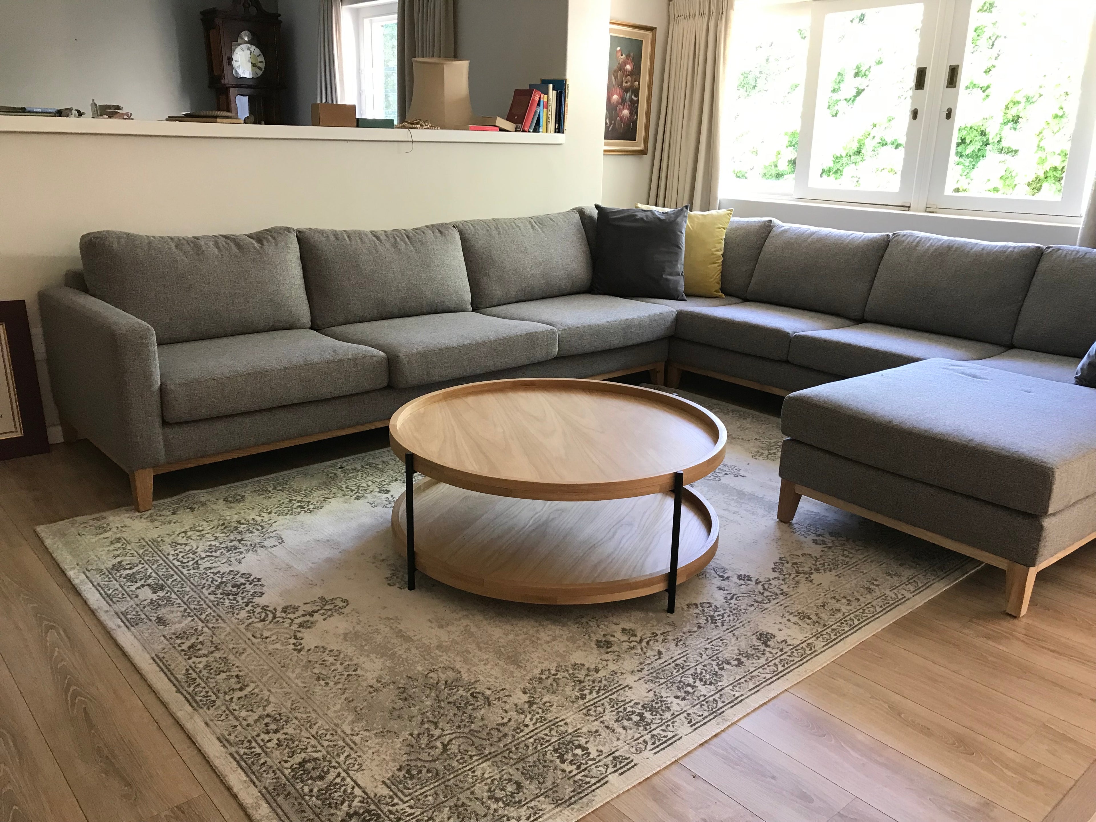 Double tiered round oak coffee table with black tubular frame and legs in living room.
