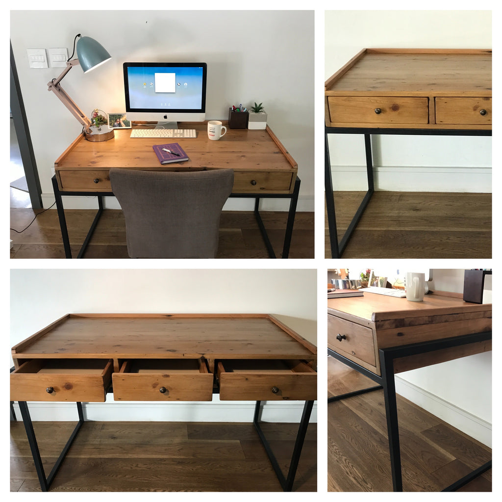 Custom made rustic pine desk with metal legs, three wooden draws, a computer monitor and keyboard for working.