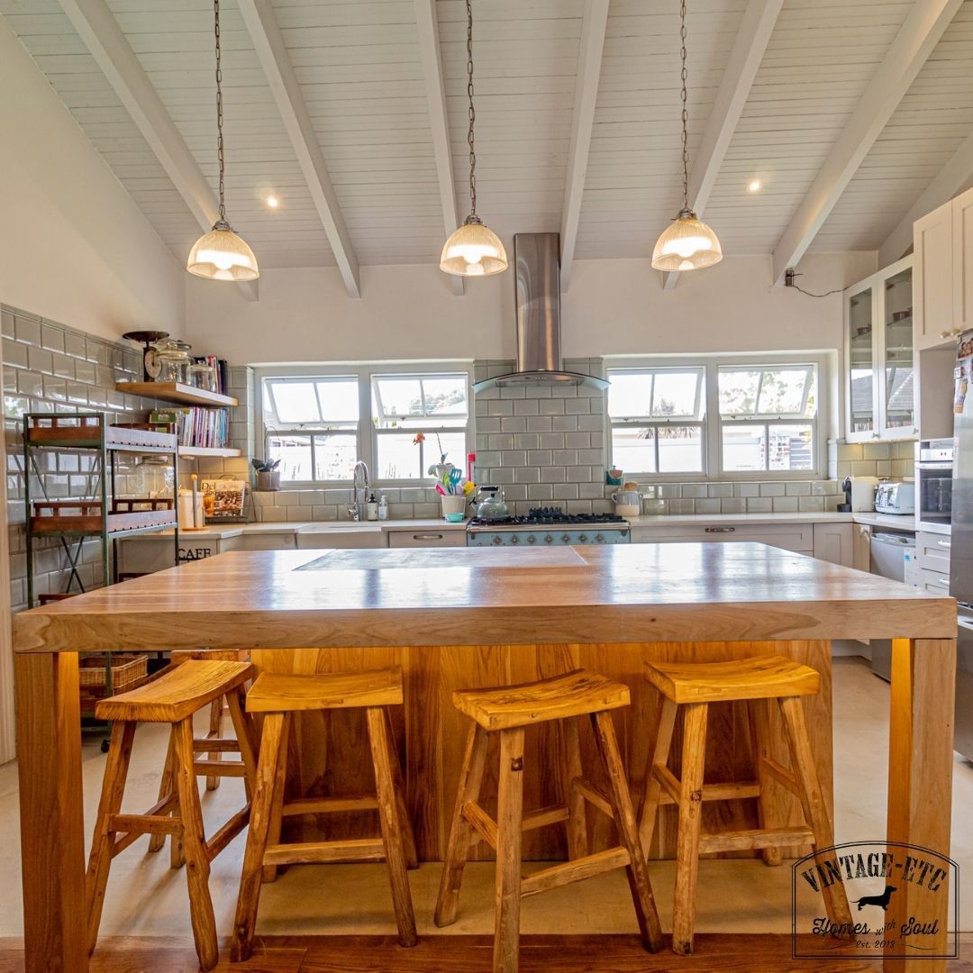Modern style kitchen with a solid oak sharing island, under-counter LED lighting, and a butcher's block countertop. The island is accompanied by a gray cabinet with a wood countertop and a hanging pendant lamp.