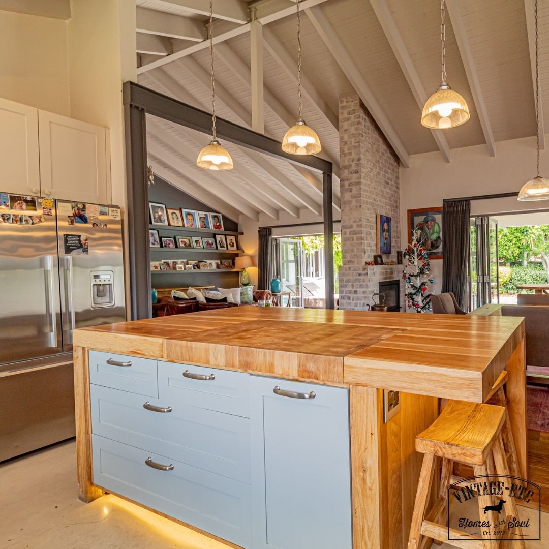 Modern style kitchen with a solid oak sharing island, under-counter LED lighting, and a butcher's block countertop. The island is accompanied by a gray cabinet with a wood countertop and a hanging pendant lamp.